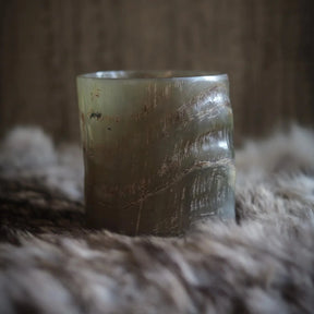 Hornglasögon för whisky fotograferad från sidan, visar transparent naturlig färg och organiska randiga mönster mot neutral bakgrund.