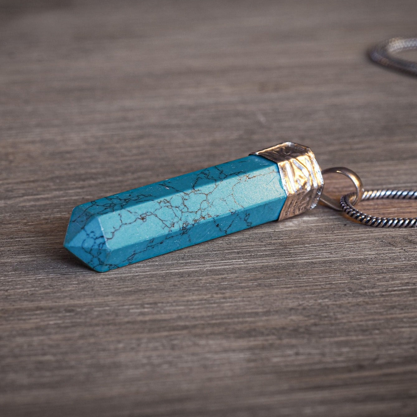 Stenhänge med Turkos - turkosblå färgad howlite på naturlig mossig skog trä, visar kristallens läknande energi