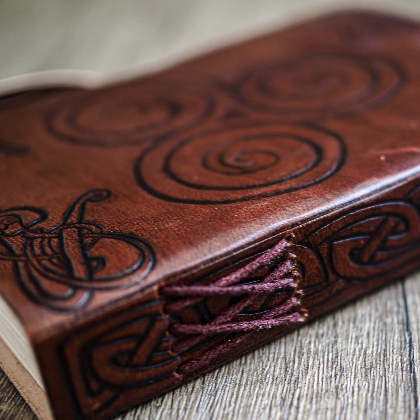 Detaljbild av ryggen på läderanteckningsbok med spiralmönster och handgjord trådbindning