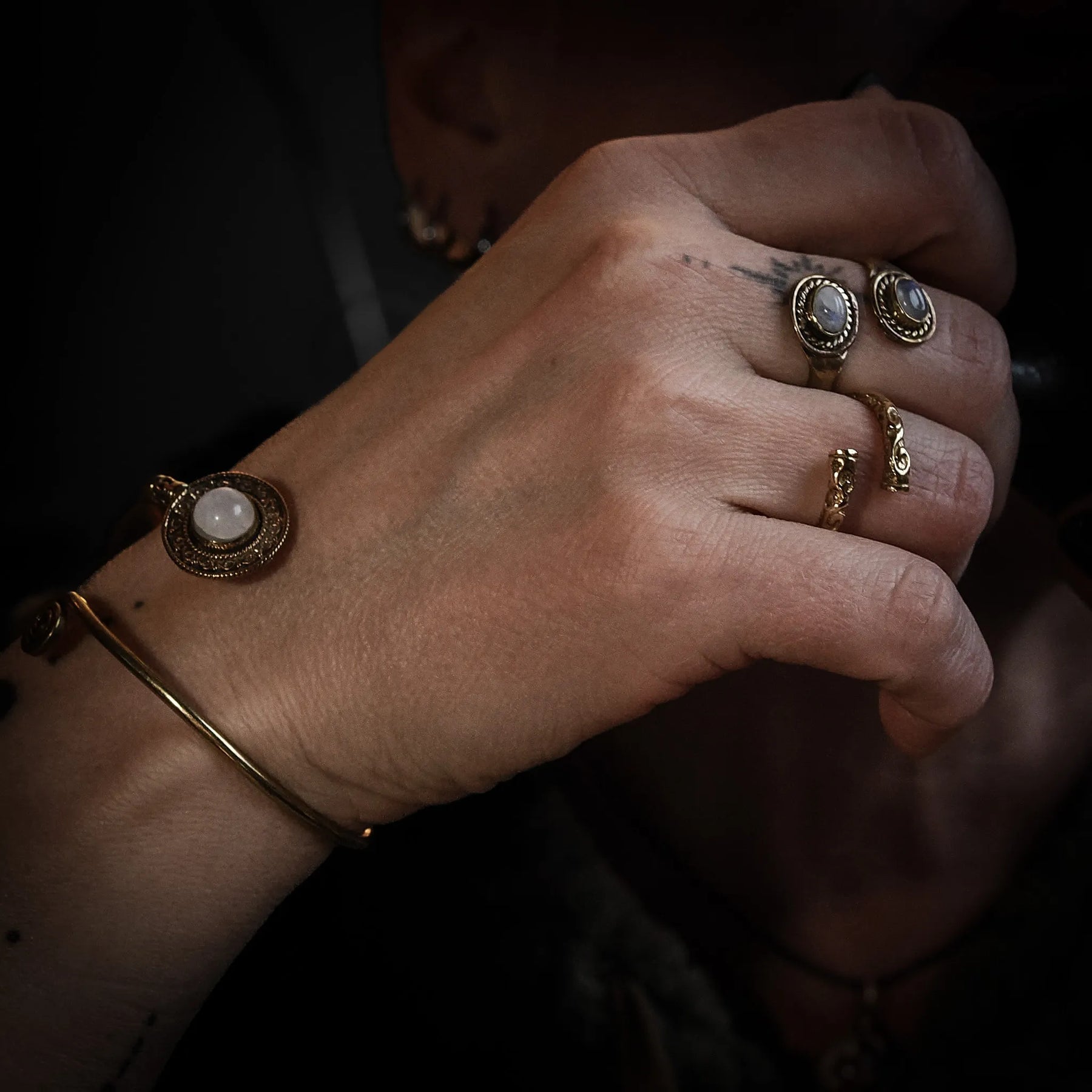 Spiralring med månstenar på kvinnohand, visad med matchande armband och ringar i antikguld