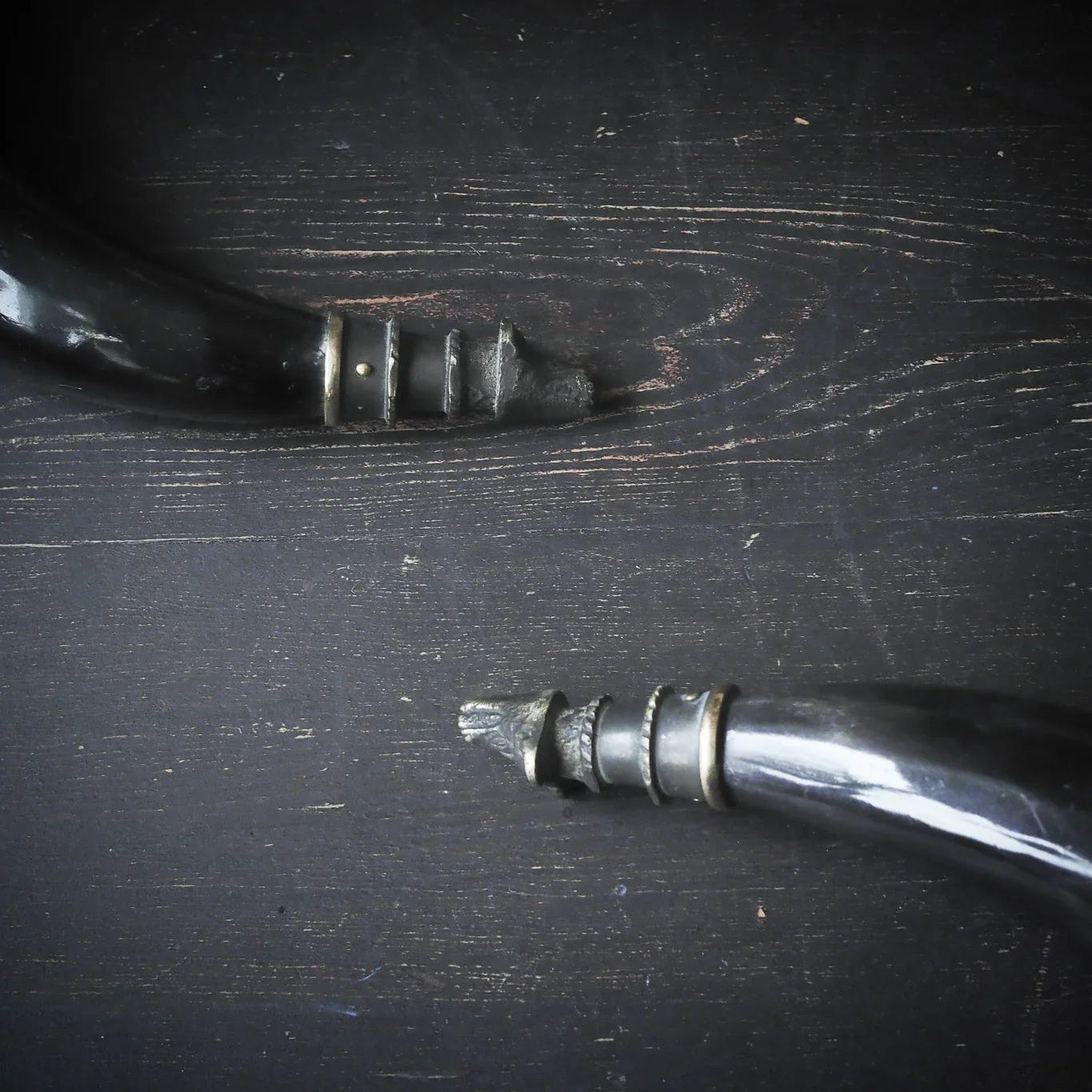 Detaljbild av mässingbandring på hornmuggen, visar metallhandverkets precision och naturlig hornstruktur
