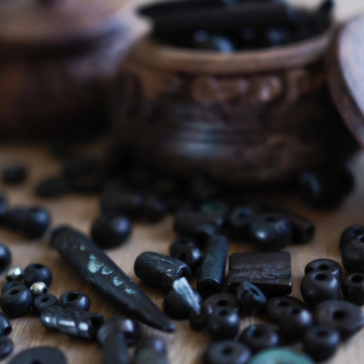 Blandning av svarta benpärlor med varierad patina. Pärlorna visar naturlig benvälling och består av cylindriska rör, sfärer och rektangulära rummare, några med mörkare döda och naturlig mineralfärgning.