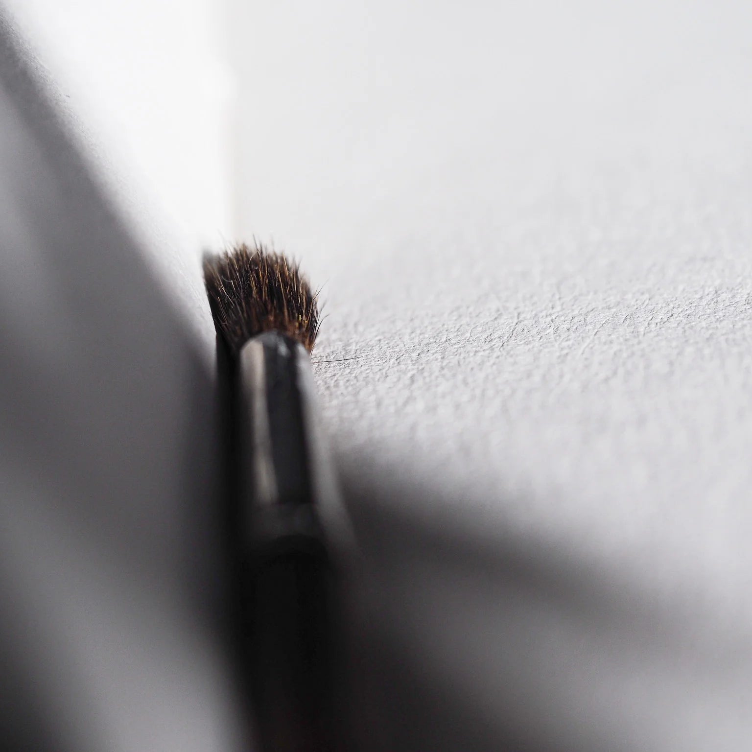 Extremnärbild av målarpenselborst på vitt pappersytor, visar naturligt djurhår och fiberstruktur