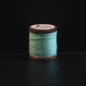 Sort broderitråd på trætromler med Nordlys-logo. Klassisk farve til traditionel vikingeinspireret broderi og formel skandinavisk tekstilkunst.