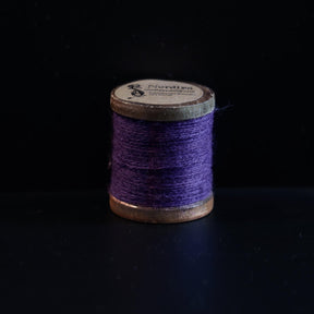 Lilla broderitråd på trætromler med Nordlys-mærkning. Dyb lilla farve perfekt til traditionelt vikingebroderi og tekstiler.