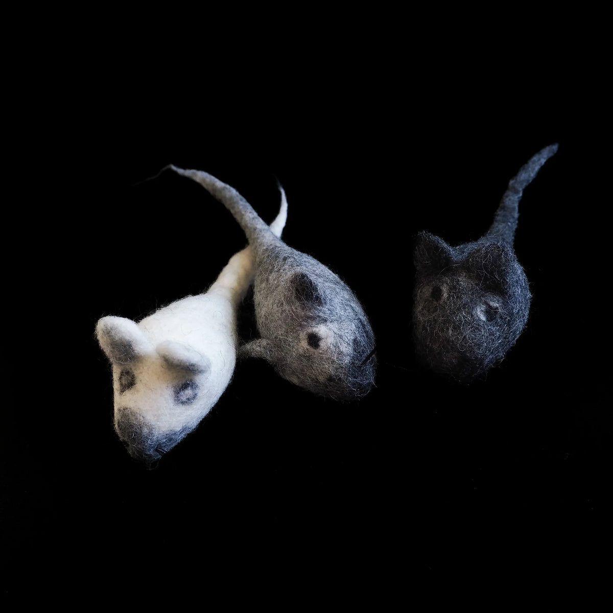 Three handfelted wool mice in light grey, medium grey, and dark grey/charcoal colors, shown in profile on black background