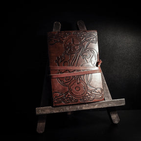 Läderbunden anteckningsbok med präglat vargmotiv och keltiska knutar, ståendes på träställ