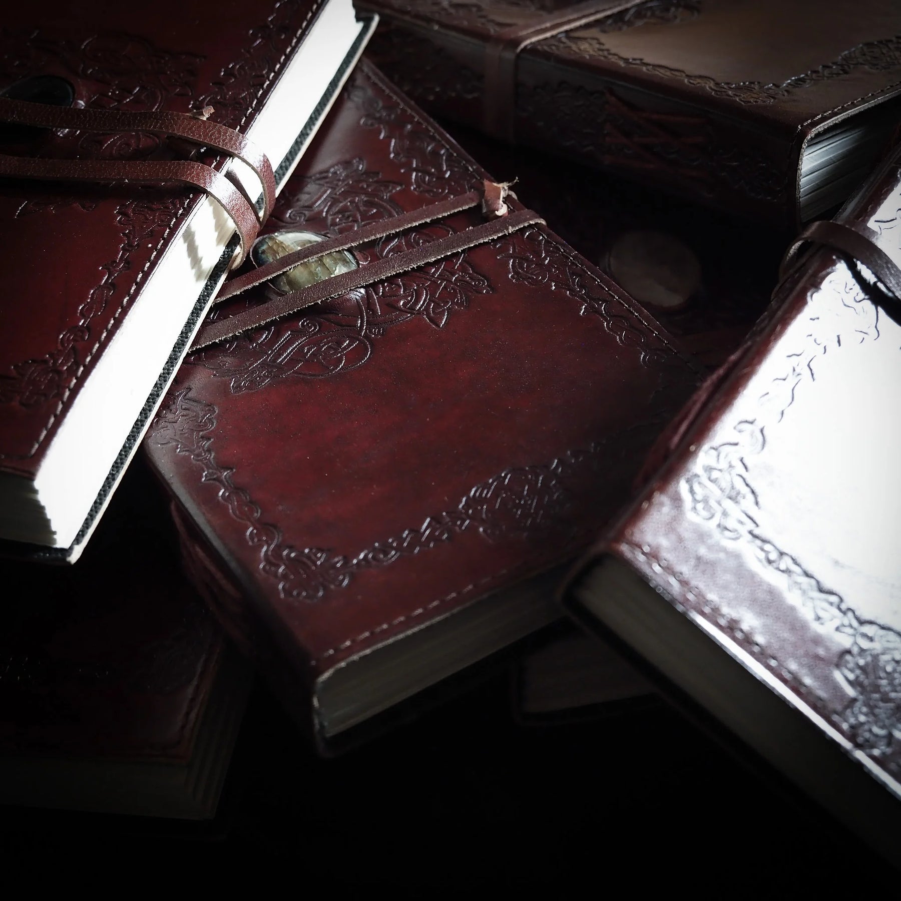 Tre bruna lädernotisar staplade med vikingmönster och kristaller, närbild