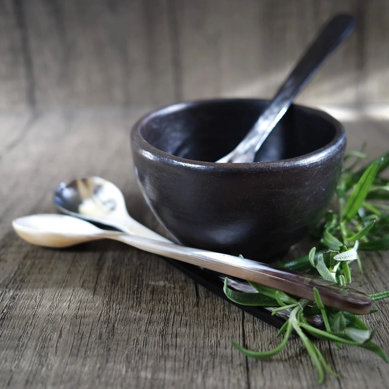 Långtesked i organisk ko-horn, liggande i svart keramik-skål med rosmarin