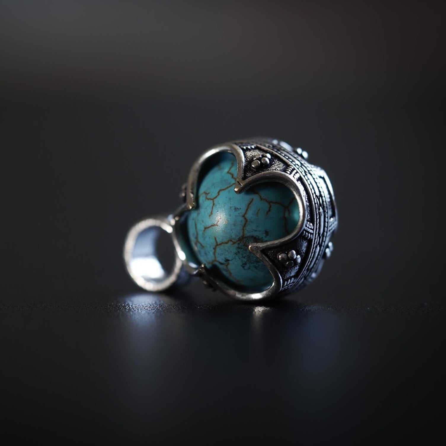 Gotländsk mässinghänge med turkos-sten, visar ornamental silverglansigt metallarbete och stenens naturliga veningar