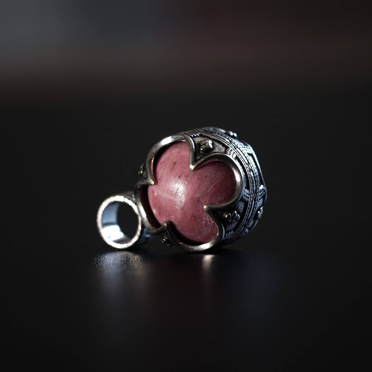 Gotlandshänge i silver med rosa jordgubbsagat synlig genom bladformad fattning mot svart bakgrund