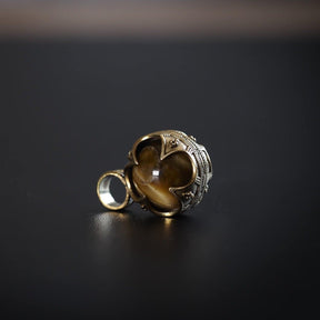 Silverpläterad gotlandshänge med oval tigeröga. Stenen skiner med varmt gul-brunt ljus och är omgiven av finmönstrad silvermontering med vikingiska dekorutlöpningar.