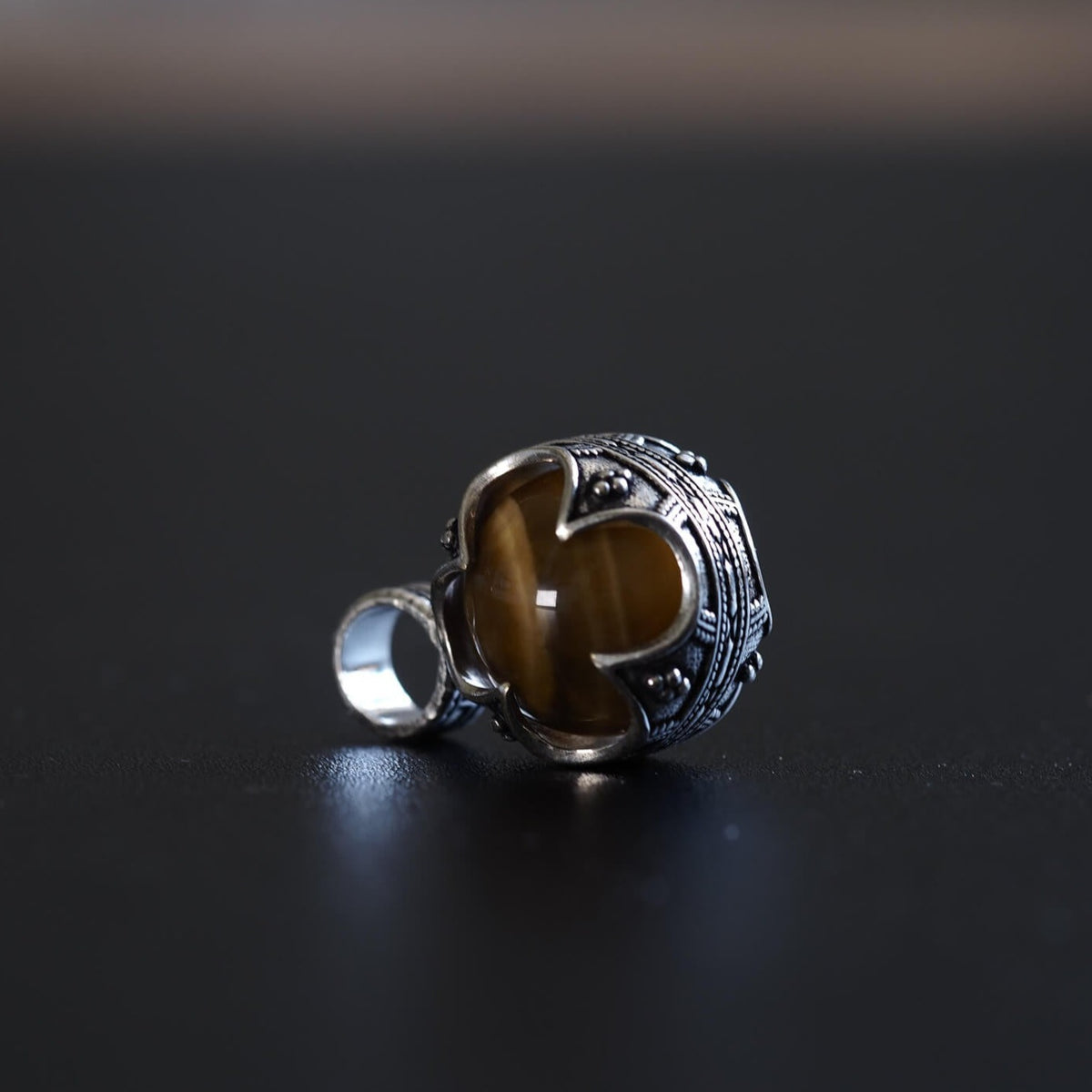 Silverpläterad gotlandshänge med tigeröga. En mörkbrun kattögesten med optisk glans är infattad i en ornament silvermontering med vikinginspirerande mönster och texturerade detaljer.