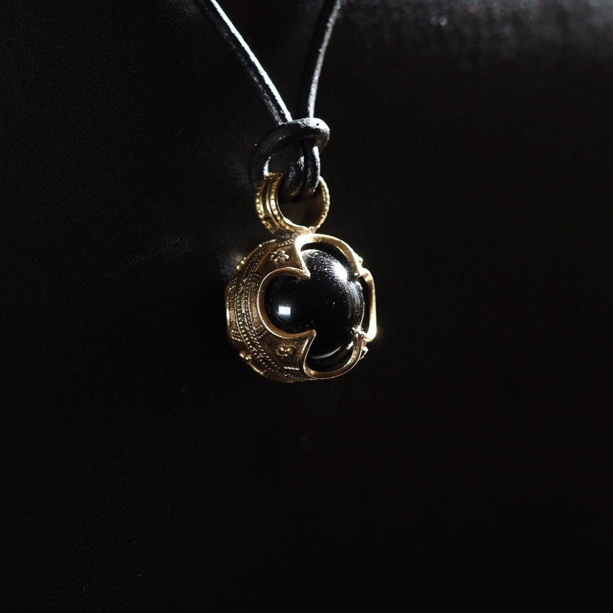 Gotlandshänge-hänge med svart agat, fotograferat från sidan för att visa djup och textur. Silverpläterad ram med vikinginspirerad geometrisk design och linjemönster.