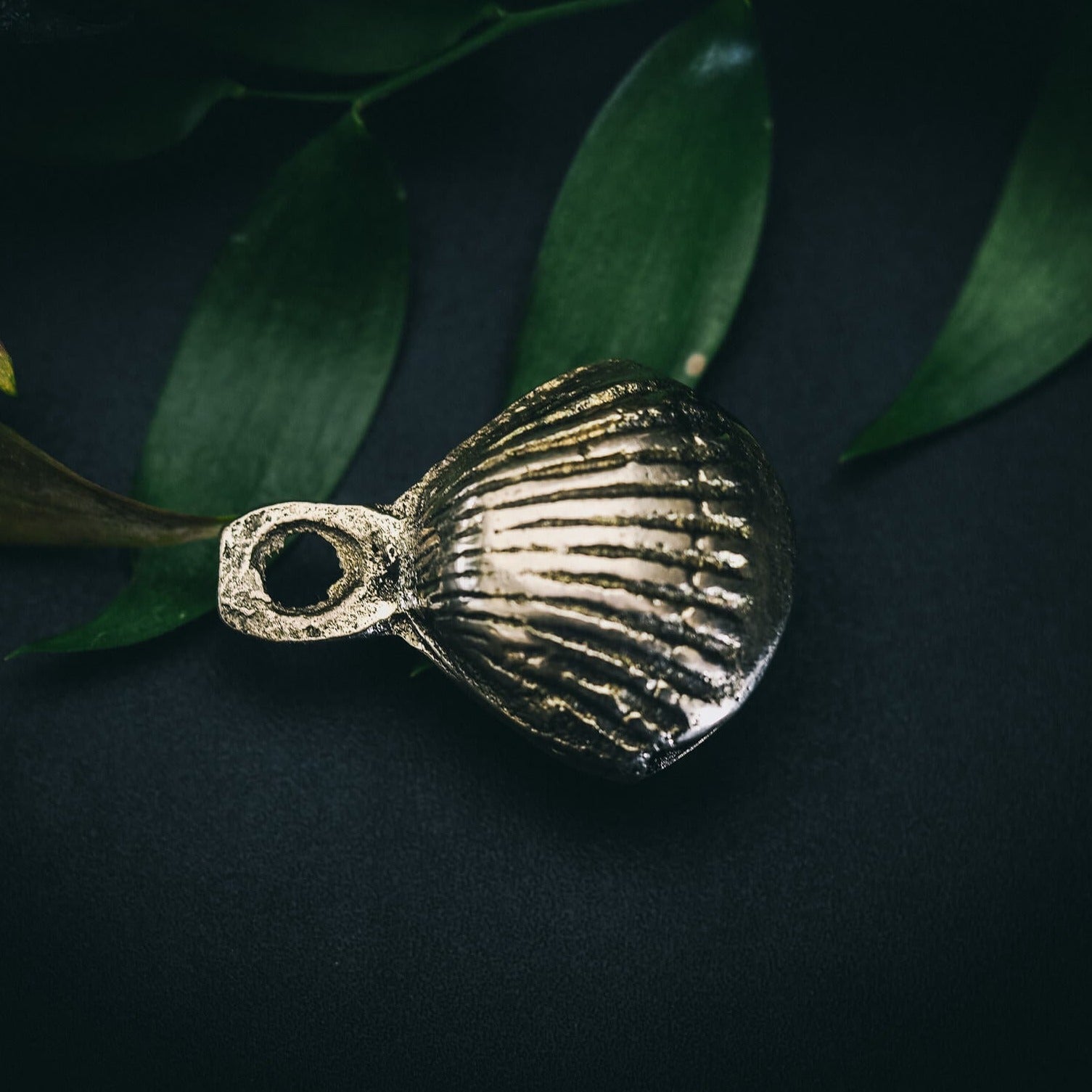 Mässingbjällra 40mm Prickar variant med djupa horisontella ridor. Makrofoto visar oxiderad mässingytan och antik patina mot grön bakgrund.