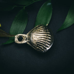 Mässingbjällra 40mm Prickar variant med djupa horisontella ridor. Makrofoto visar oxiderad mässingytan och antik patina mot grön bakgrund.