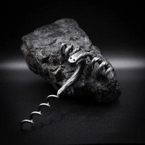Handsmide bagge-skruv (råmskruv) på granitatsten. Gjord av återvunnet järn med mörkpatina och metalliska högdagrar. Baggehuvudet visar böjda horn som formar dramatisk handtag. Ansiktsfötryck och öga-detaljer synliga. Spiral skruv nedan. Dramatisk sidbelysning betonar metallartverk och hantverk.