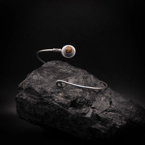 Upper arm ring with dark black/charcoal stone in silver-plated brass bezel setting, adjustable open cuff with decorative wire elements