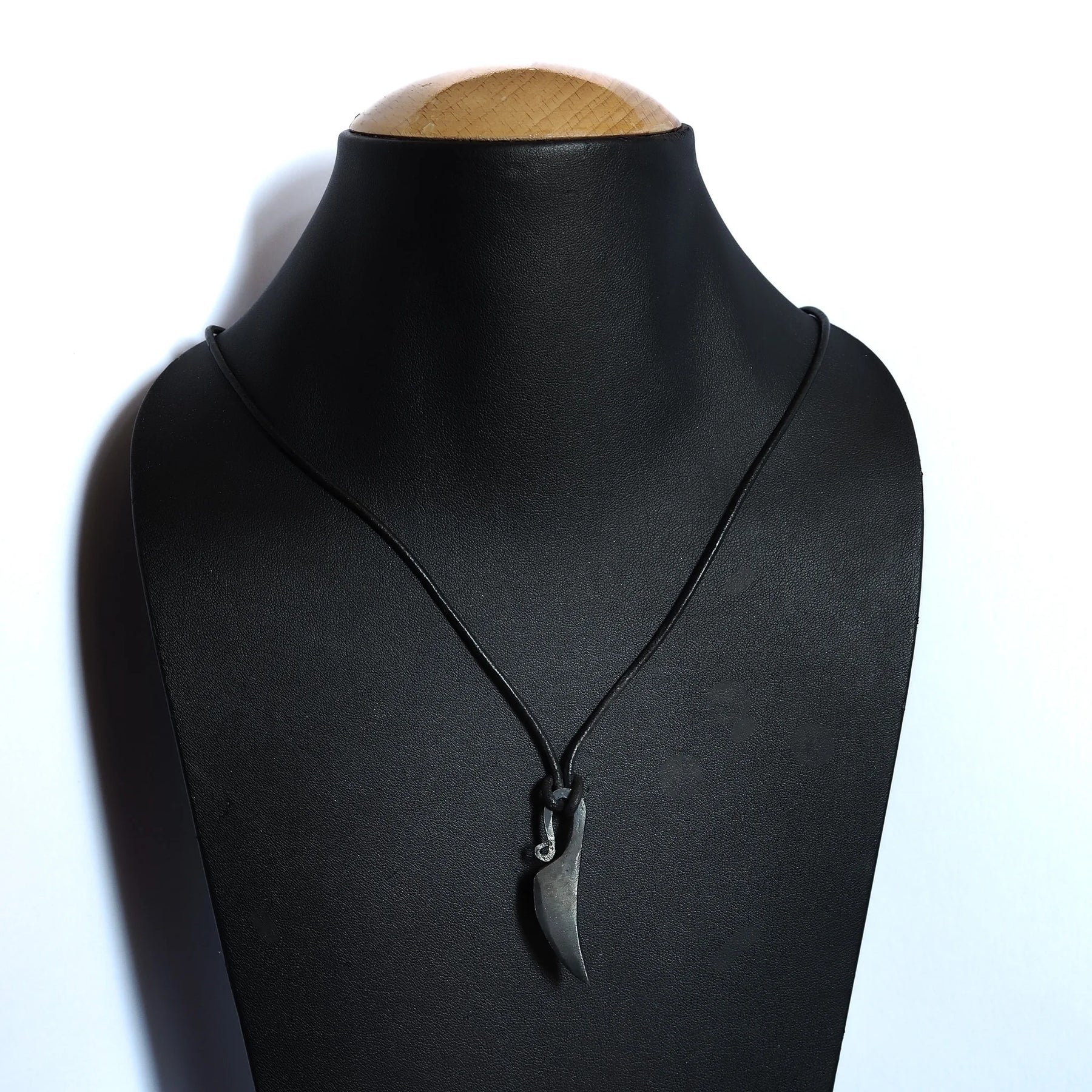Kvinnokniv mini presenterad som färdigt halsband på svart mannekängbyst. Två strängar av mörk lädersnöre sträcker sig från hängesmycket. Visar hur pendant bärs.