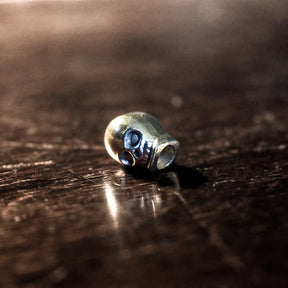 Silver beard bead with detailed skull and decorative side flanges, macro photography