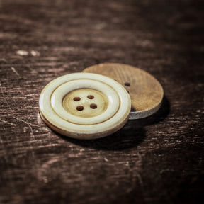 Stor benknapp med mörkare bakgrund, visar detaljerna från svarvararbetet och de naturliga färgskiftningarna i benet