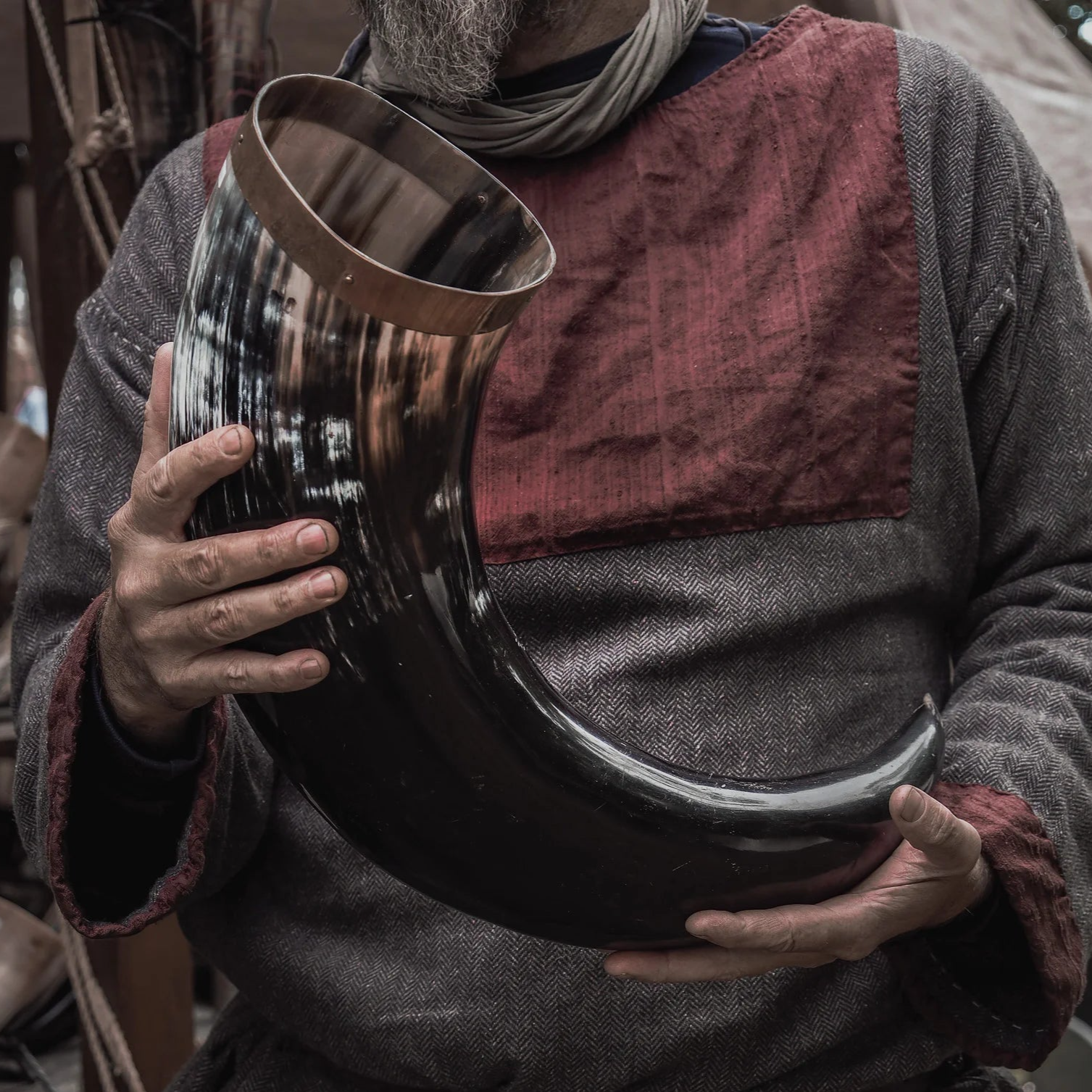 Stort vikingadryckeshorn på cirka 4-5 liter med mässingsdekor, hållet av person i historisk vikingatida klädsel. Visar hornets naturliga mörkbrun färg och skala för användning.
