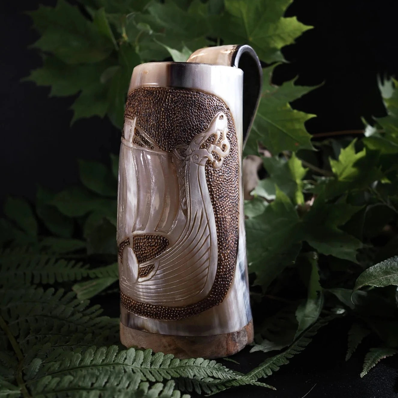 Hornmugg med vikingskepp, fotograferad från sidan för att visa skärningens detaljer och skeppets segel.
