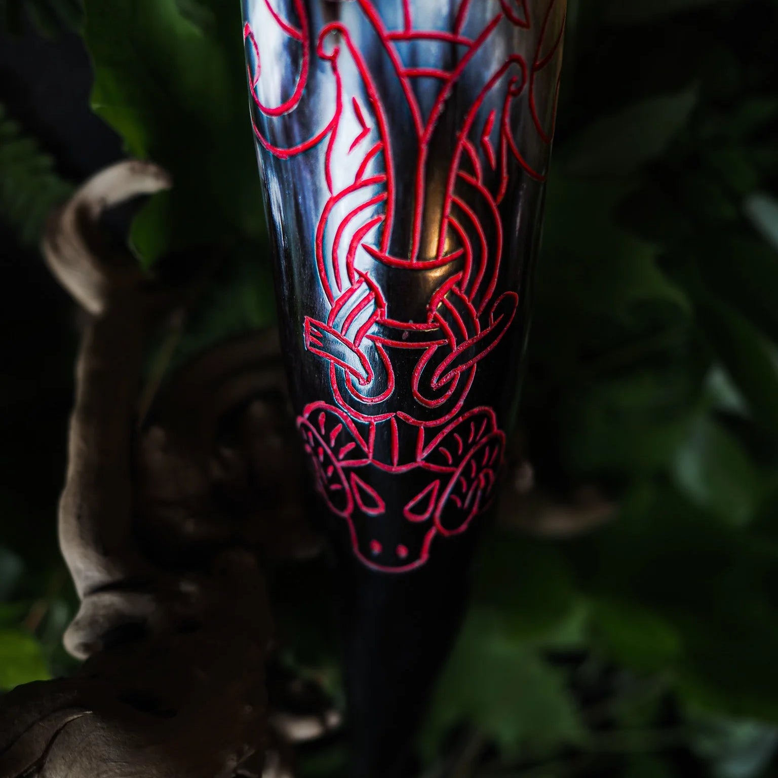 Närbild av hornets graverade yta med livfulla röda infärgningar som framhäver det intricata norska knotwork-mönstret. Djupa snidningar visar flera lager av geometriska mönster.