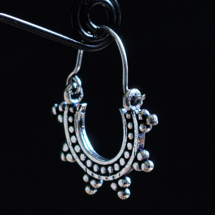 En liten solinspirrerad örhänge i silveröverlagring mässing med ornamental design och hängande detaljer