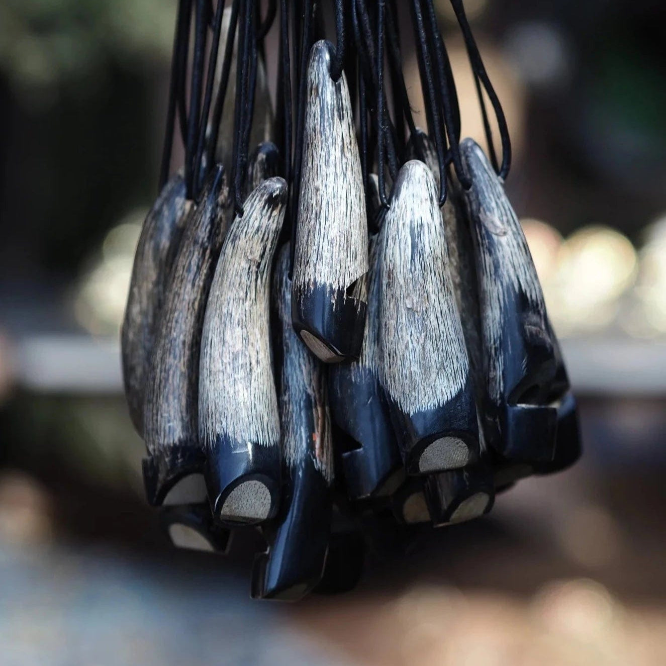 Makrofotografi av flera visselpipor visar de hantverk-gjorda benspetsarna med naturlig kornstruktur och ljus färg. Mörka hornutgångshål synliga. Visar detaljnoggrannhet och materialkvalitet.