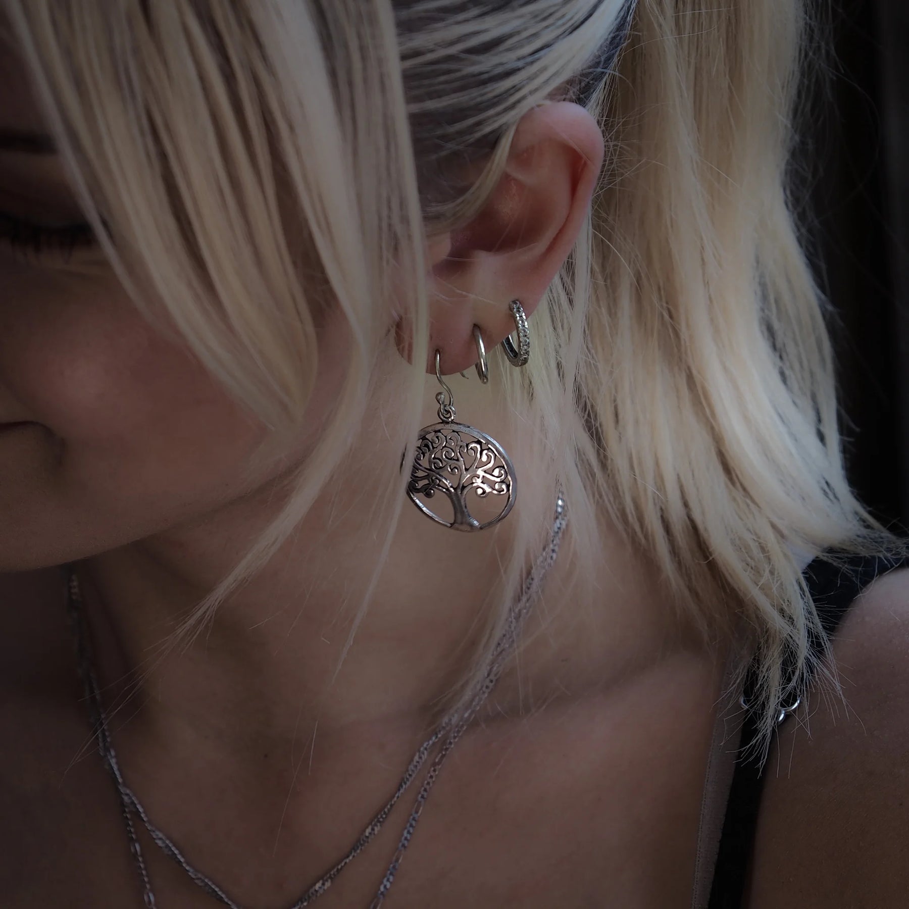 Silverfärgad Tree of Life/Yggdrasil-örhängsmycke på öra, med detaljerat träd- och rotmotiv