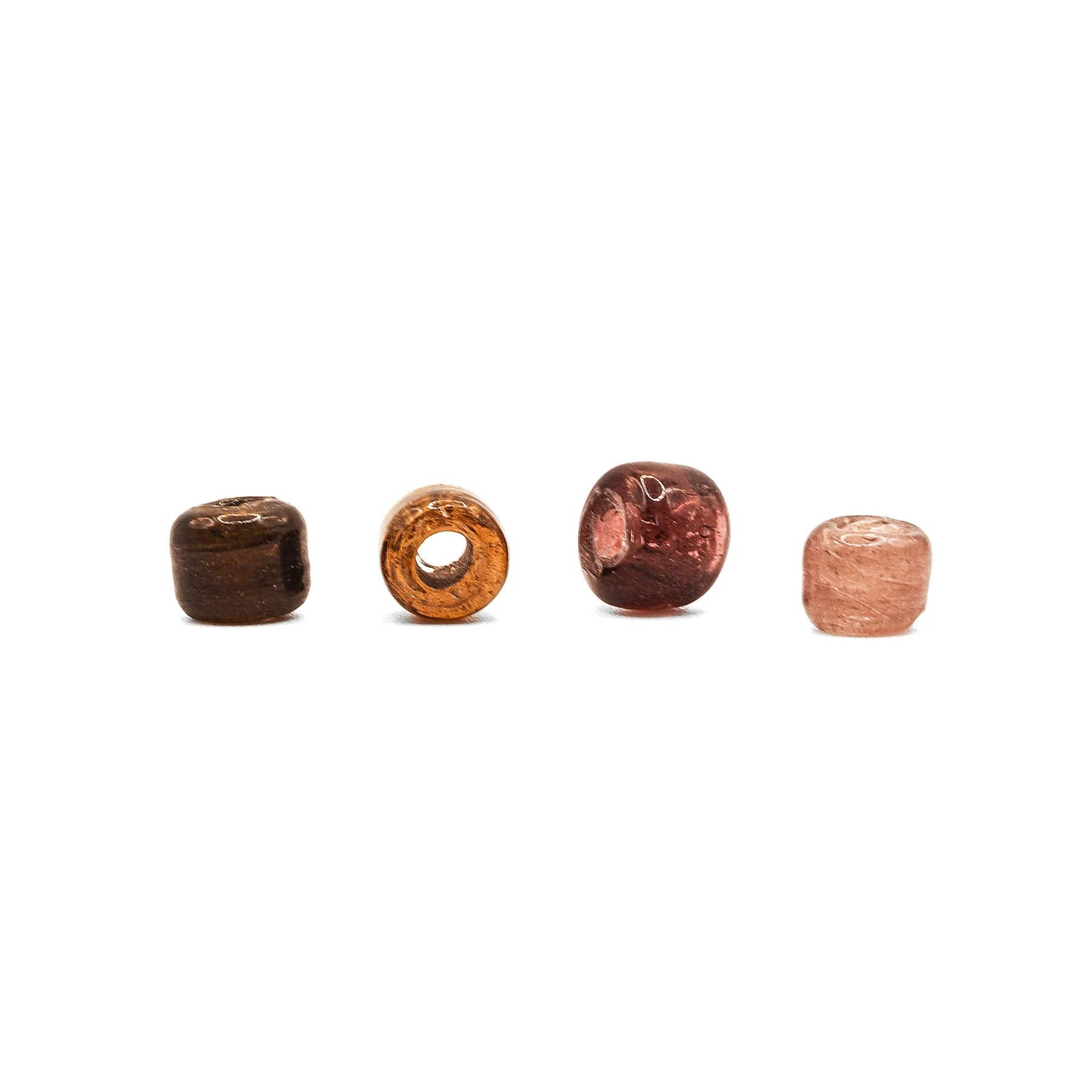 Fyra antika glaspärlor i mörkbrun, orange, röd och rosa färg presenterade på vit bakgrund