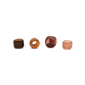 Fyra antika glaspärlor i mörkbrun, orange, röd och rosa färg presenterade på vit bakgrund