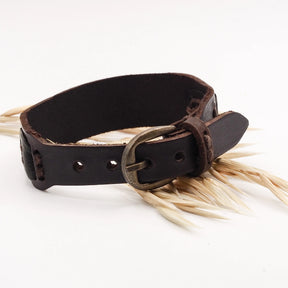 Brunt läderarmband på vit bakgrund med torrt hö, visar äkta material och naturlig åldring
