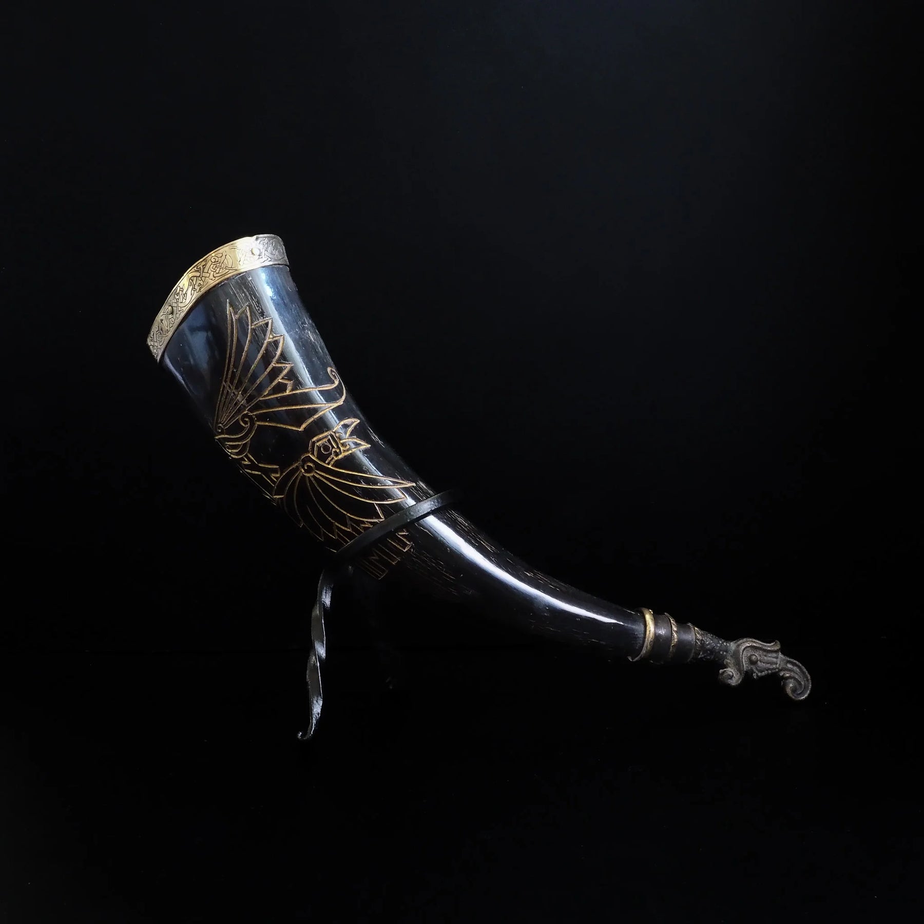 Dryckeshorn profilering med utbredda vingar på en graverad korp. Organiskt horn med mässing och detaljerade vikingmotiv i guldlinjer.