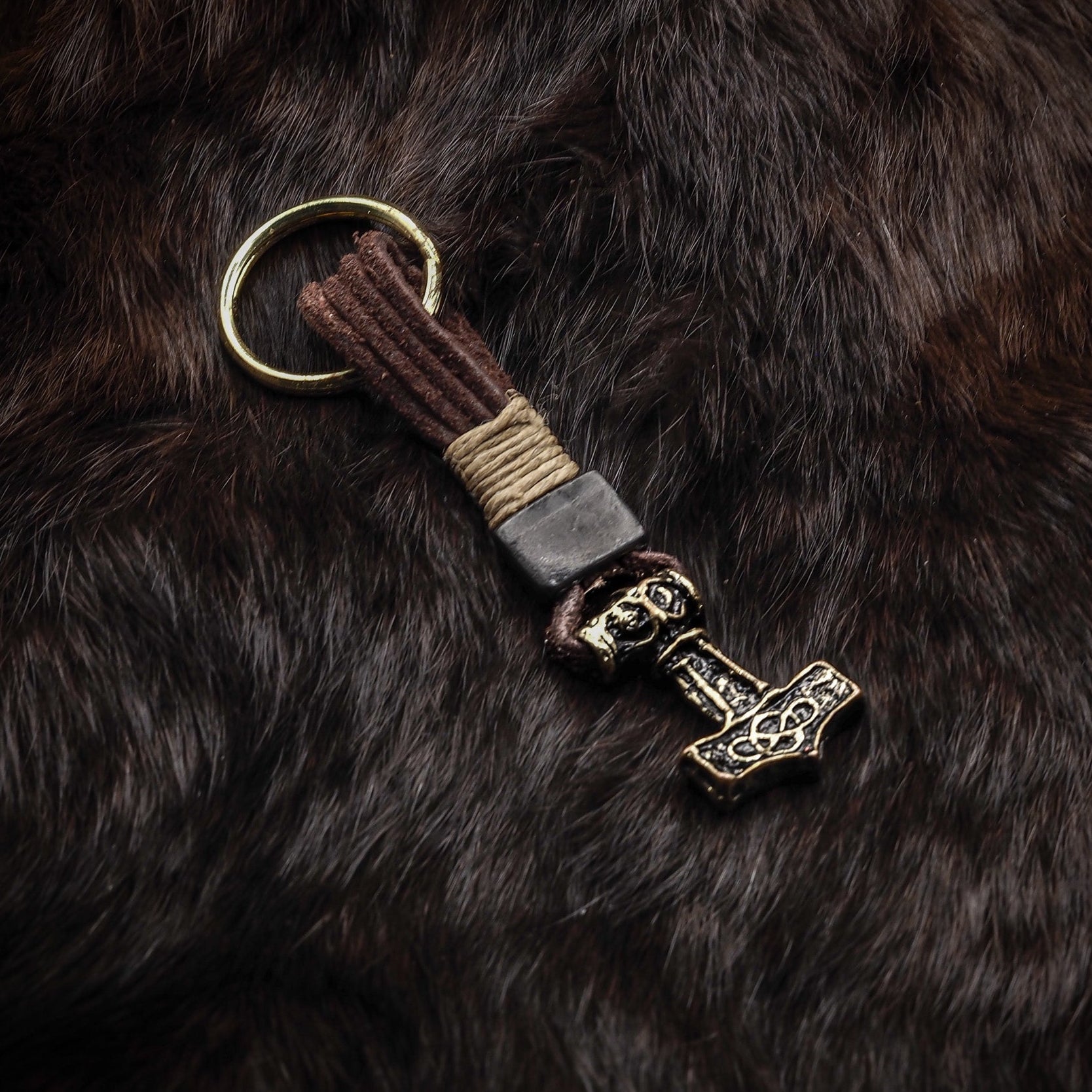 Samma Torshammare-nyckelring på mörkare botten, visar patinerad brons och läderbandet.