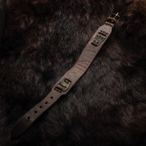 Överblick av brunt läderarmband med metallnitar på mörk bakgrund, visar full längd och detaljerad konstruktion