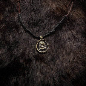 Halsband gudinnan Freja bärat mot mörkoch textilbakgrund, mässingsamulett med bi-motif på läderrem.