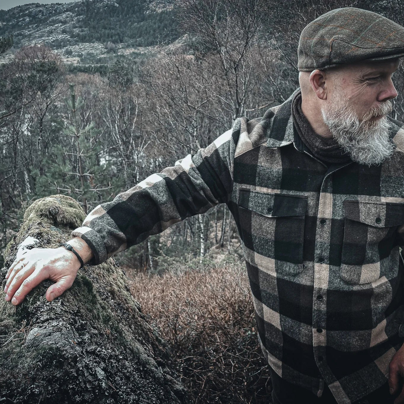 Eitre Vikingaarmband på mans handled mot kustnär miljö med väderbitna stenar, visar armbandets hållbarhet