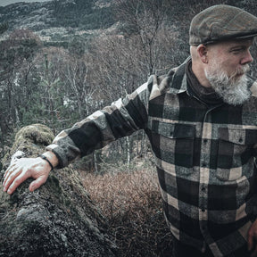 Eitre Vikingaarmband på mans handled mot kustnär miljö med väderbitna stenar, visar armbandets hållbarhet