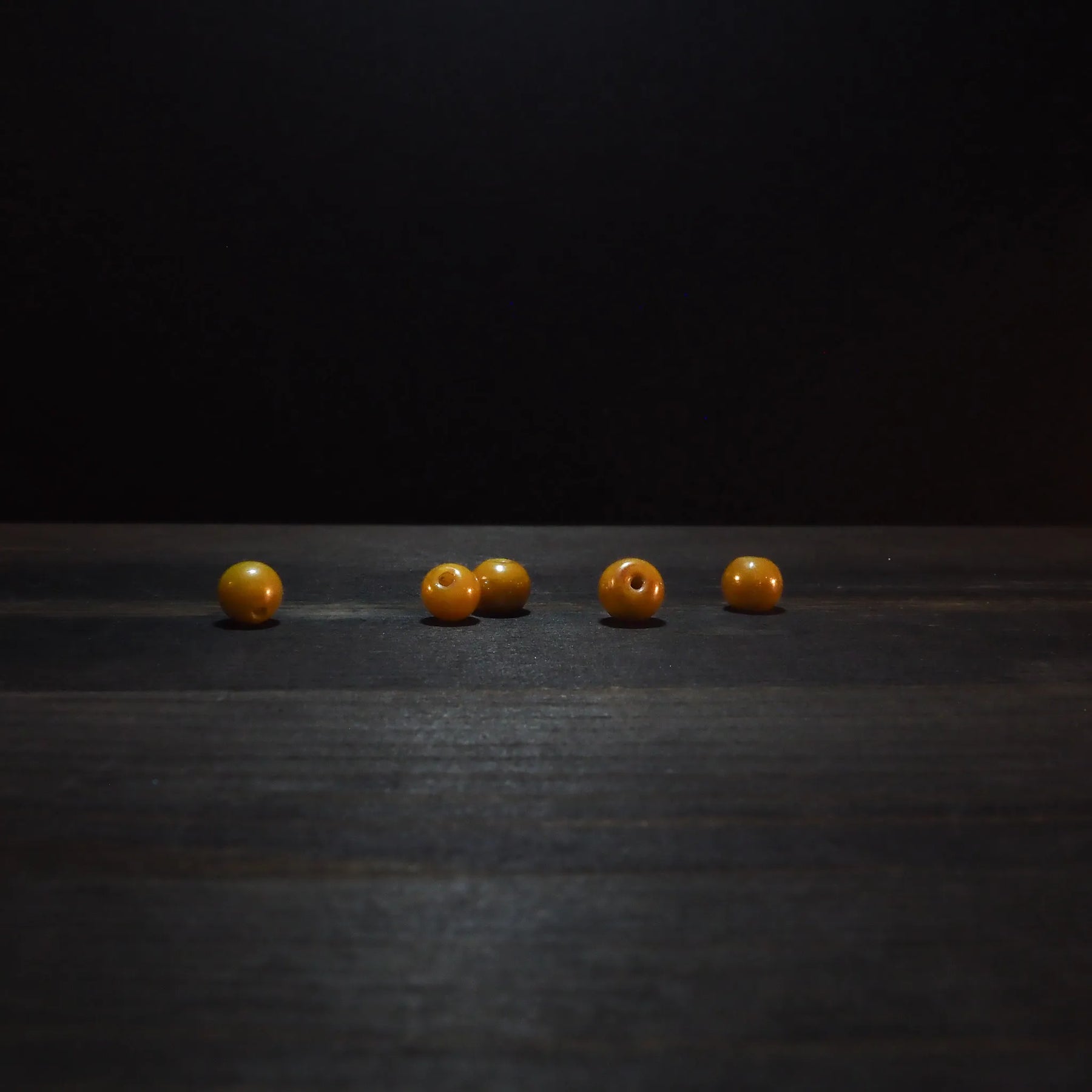 Golden yellow round glass beads, 6mm diameter, displaying polished finish and drilled holes for jewelry making