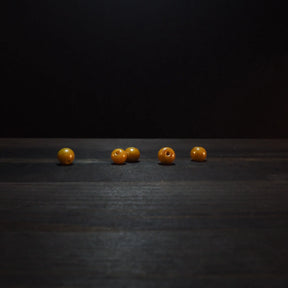 Golden yellow round glass beads, 6mm diameter, displaying polished finish and drilled holes for jewelry making