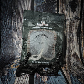 Fyra paket vikinggodis med Mjölnir-formade sura karameller arrangerade på trä. Paketen är röda, svarta och beiga med silvrig text.