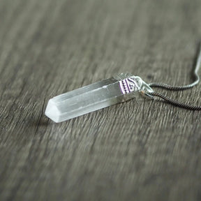 Selenit stenhänge - translucent vit kristall med mässingsfäste på mjuk bakgrund