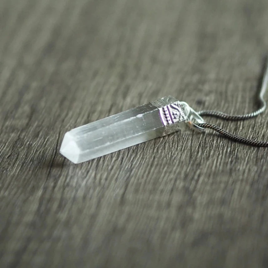 Selenit stenhänge - translucent vit kristall med mässingsfäste på mjuk bakgrund