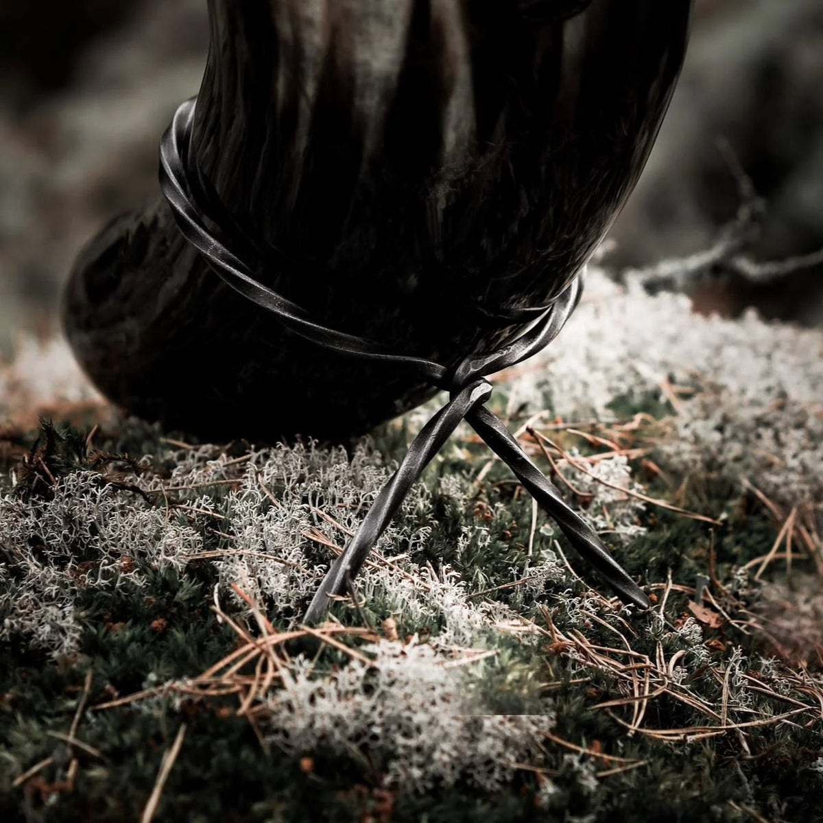 Studio-fotografi av dryckeshorn 800 ml på svartoxiderat handsmidett järnställ. Visar hornets genomskinlighet och järnställets tripod-bendesign.