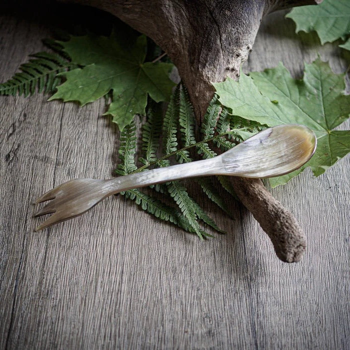 Trädspork på träunderlag omgiven av gröna ormbunksblad, handsnidad från naturligt trä