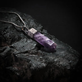 Ametisthänge i rå kristallform med silverfärgat mässingsfäste, upphängd på silvrig kedja mot mörk bakgrund