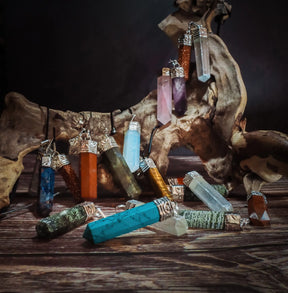 Stenhänge berlocker - samling av kristallhängen i olika färger inklusive labradorit, turkosmålad howlite och andra naturstenar monterade på trä