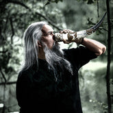 Livsstilsfotografi av dryckeshorn med vikingaskepp pyrografi. Visar händer som håller hornet för drickande, med detaljerat snidmönster av segelfartyg.